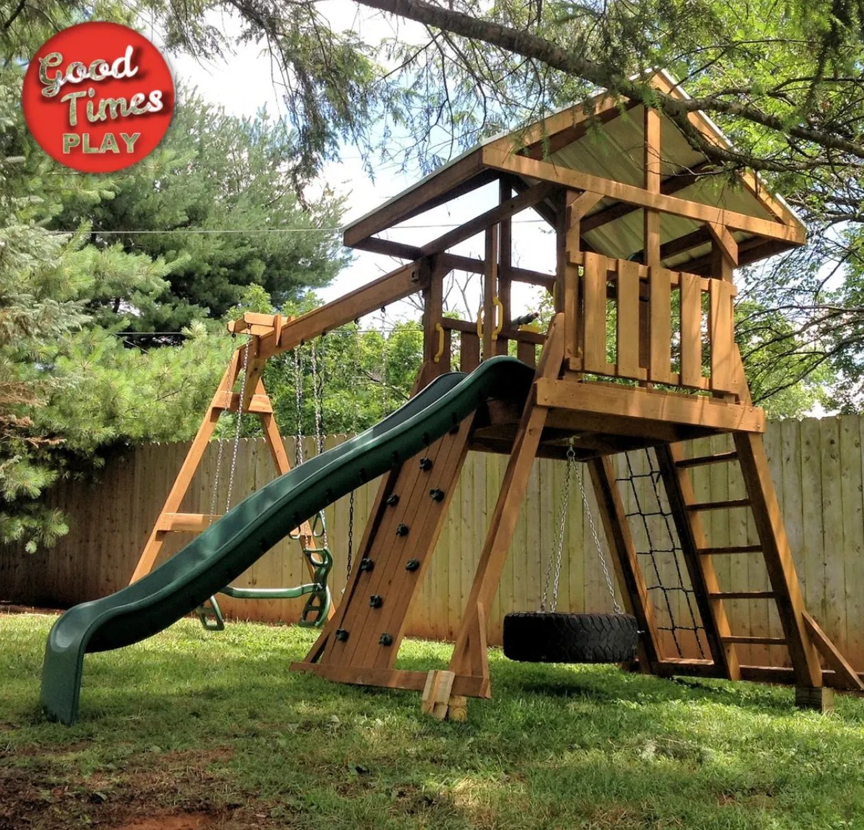 Wooden backyard playset with slide, swings, climbing wall, and tire swing