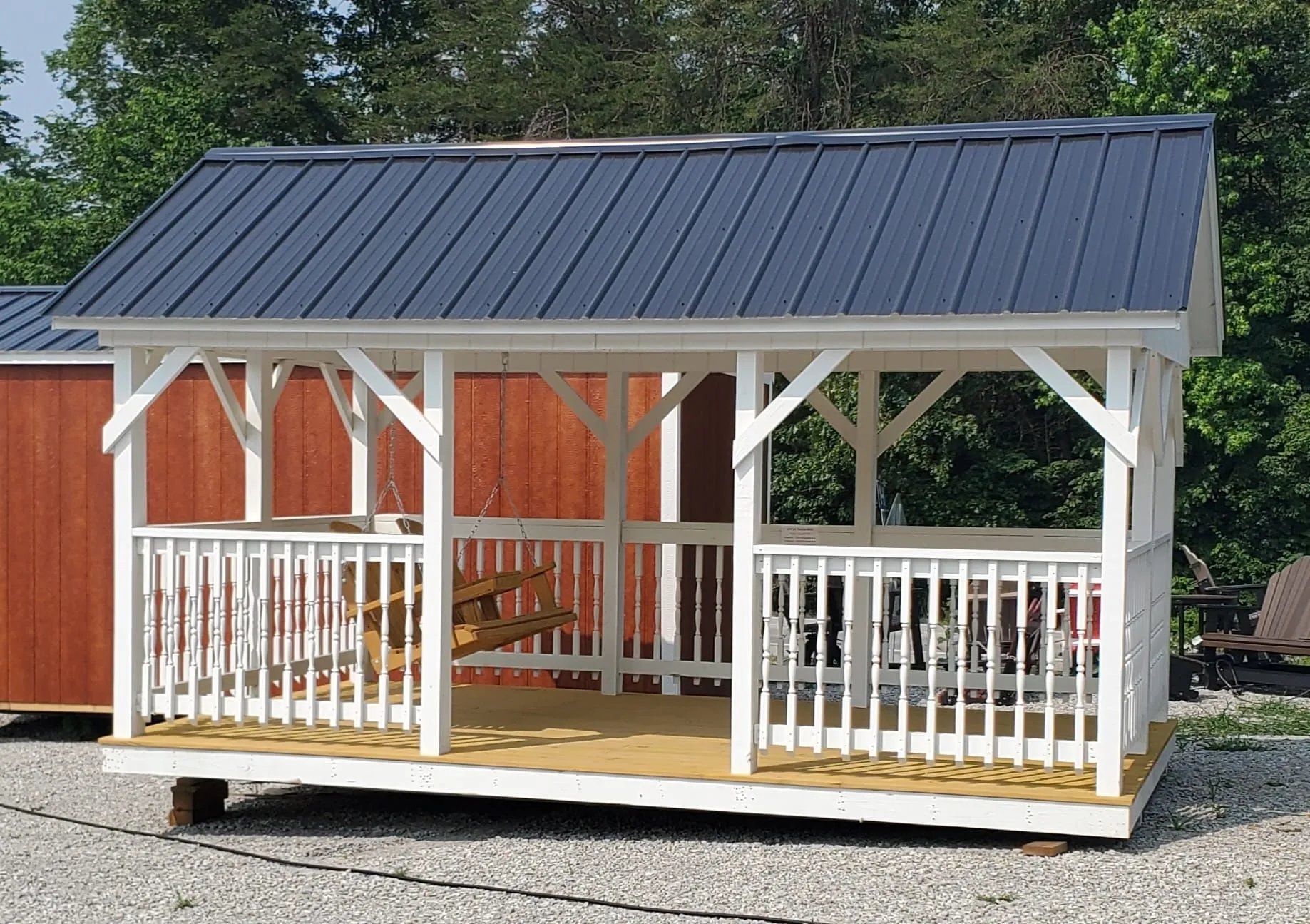 White and orange wooden shed with blue metal roof and porch swing